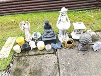 Full lot laid out on patio showing all statues, pots, birdhouse, plaque and ornaments