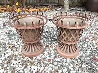 Front view of both metal lattice urn planters on gravel ground