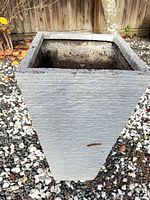 Tall rectangular concrete planter front view showing ribbed texture and weathering