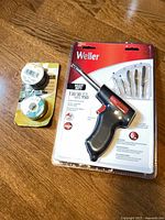 Front view of sealed Weller TB100 kit alongside two solder spools