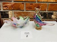 Candy bowl and bird figurine side by side on white surface