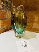 Front angled view showing amber-to-green gradient, ribbed body, clear base, ruffled rim