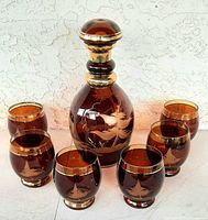 Full view of decanter and six glasses showing etched design and gold trim