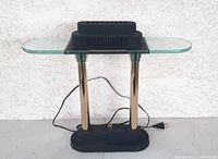 Front view of Sonneman desk lamp showing brass columns, black housing, glass wings