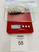 Nine Barber silver coins in bag on scale reading 77.9 g
