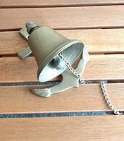 Side view of brass bell on anchor bracket with chain