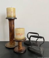 All items together: two sad irons, two wooden spools, two candles
