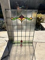 Full view of stained glass window leaning outdoors showing overall pattern and colours