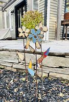 Front view of three metal flower stakes in garden bed
