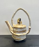 Full view of teapot showing overall sculptural form, arched handle and spout