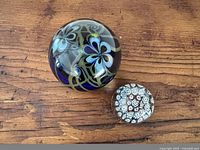 Both paperweights side by side on wood surface