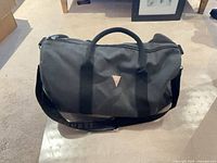 Full view of Guess charcoal duffel with shoulder strap and handles