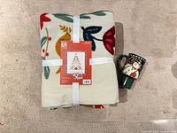 Blanket folded with tag and ribbon plus mug beside it