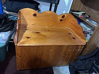 Front view of knotty pine storage bench showing scalloped back, planked front, surface wear