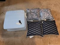 stacked light blue seat cushions next to four pillows showing different patterns