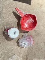 All three Tupperware items in sealed plastic: red colander, clear shaker, packaged Mate set