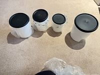 Four canisters side by side, three still in plastic and lids on