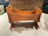 Side view of wooden doll cradle showing rocker base and side panels