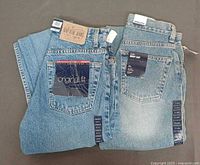 Two pairs of Gap blue denim jeans laid flat showing back pockets and tags