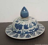 Side view of porcelain covered dish showing lid, finial, plate, blue and white decoration