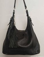 Front view of black leather handbag showing tassel, texture and overall shape