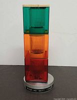 Front view of Patlite signal tower showing green, amber and red lenses and base label