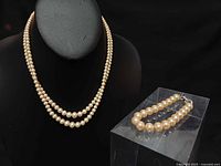 Necklace displayed doubled on bust form with bracelet on acrylic stand showing overall appearance and bead luster