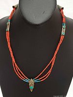 Full view of three-strand coral and turquoise bead necklace on display bust
