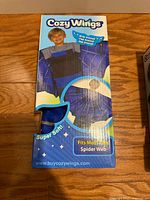 Front of sealed Cozy Wings box showing spider web design and product details