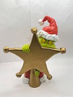 Front view of Grinch tree topper holding gold star