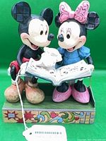 Front view of Jim Shore Mickey & Minnie “Sharing Memories” figurine on patterned base with tag