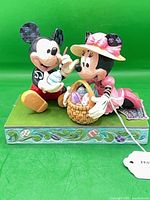 Front view of Mickey painting egg and Minnie with basket