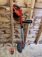 Full view of Black+Decker cordless string trimmer with battery installed and charger on floor