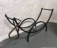 angled view of curved black metal log holder with ice tongs hanging