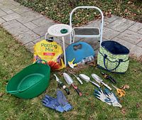 All items arranged on grass: table, stool, tote, kneeling pad, potting mix, tub, spray bottle, twine, gloves, hand tools