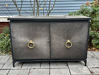 Front view of buffet table showing two starburst-textured doors with brass ring pulls