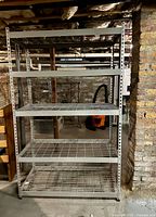 Front view of five-tier metal shelving unit showing wire-mesh shelves and steel frame