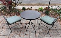 full view of table and two chairs with cushions on patio