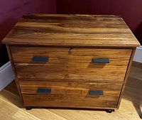 Front view of closed two-drawer walnut file cabinet on casters