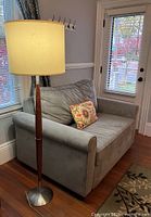 Sleeper chair beside teak floor lamp, pillow on seat