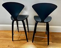 Rear and side view of both ebony Cherner stools showing shape and footrests