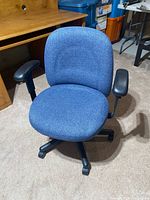 Front view of blue fabric office chair showing seat, backrest, armrests, and base