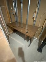 Front angle of faux wood laminate desk showing top surface, keyboard cutout, metal legs