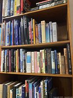 Four shelves filled with assorted hardcover and softcover books