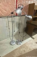 Both silver floor lamps standing side by side