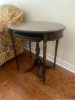 Large oval table with smaller table nested below beside a chair