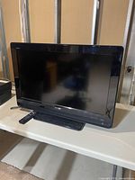 Front view of Sony 32-inch Bravia TV on stand with remote