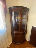 Full view of cabinet showing curved glass doors and lower storage