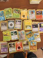 Spread of unsleeved Pokémon cards on table showing mix of Pokémon, Trainer and Energy cards
