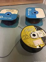 Overview of three wire spools: two Belden blue square reels with purple and brown wire, one Phalo yellow/black round reel with beige wire
